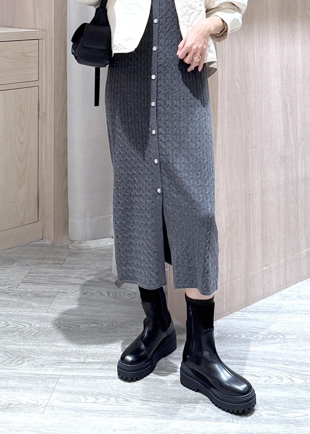 ブラック系のショルダーバッグ、ブラック系のブーツ、ホワイト系のブルゾンを着用したレディースの秋コーディネートの5枚目の写真