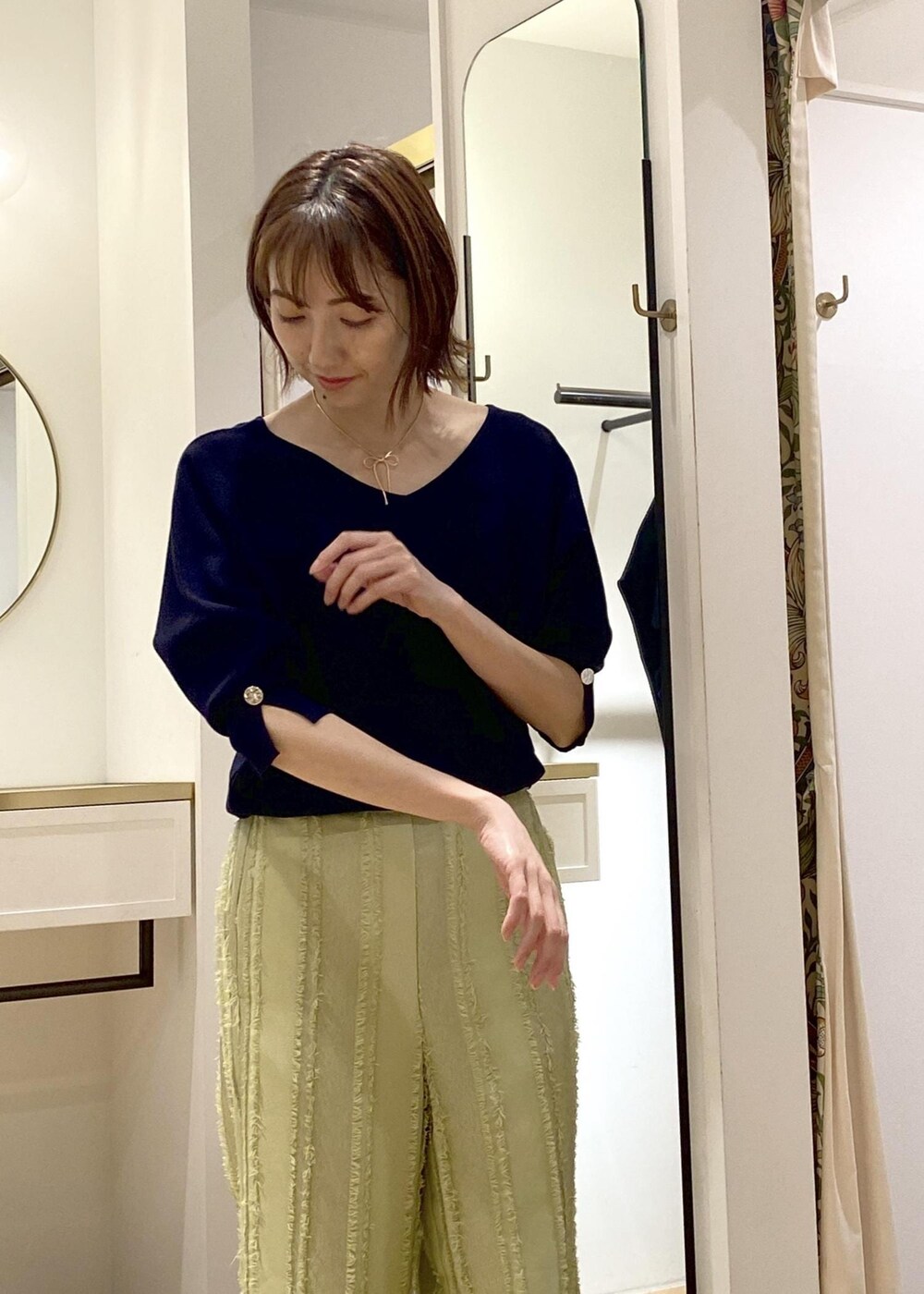 シルバー系のパンプス、グリーン系のスラックス、ブラック系のショルダーバッグを着用したレディースの春コーディネートの4枚目の写真