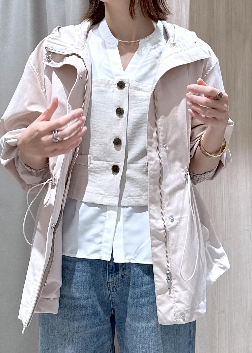 イエロー系のショルダーバッグ、ピンク系のナイロンジャケット、ブルー系のデニムパンツを着用したレディースの春コーディネートの4枚目の写真