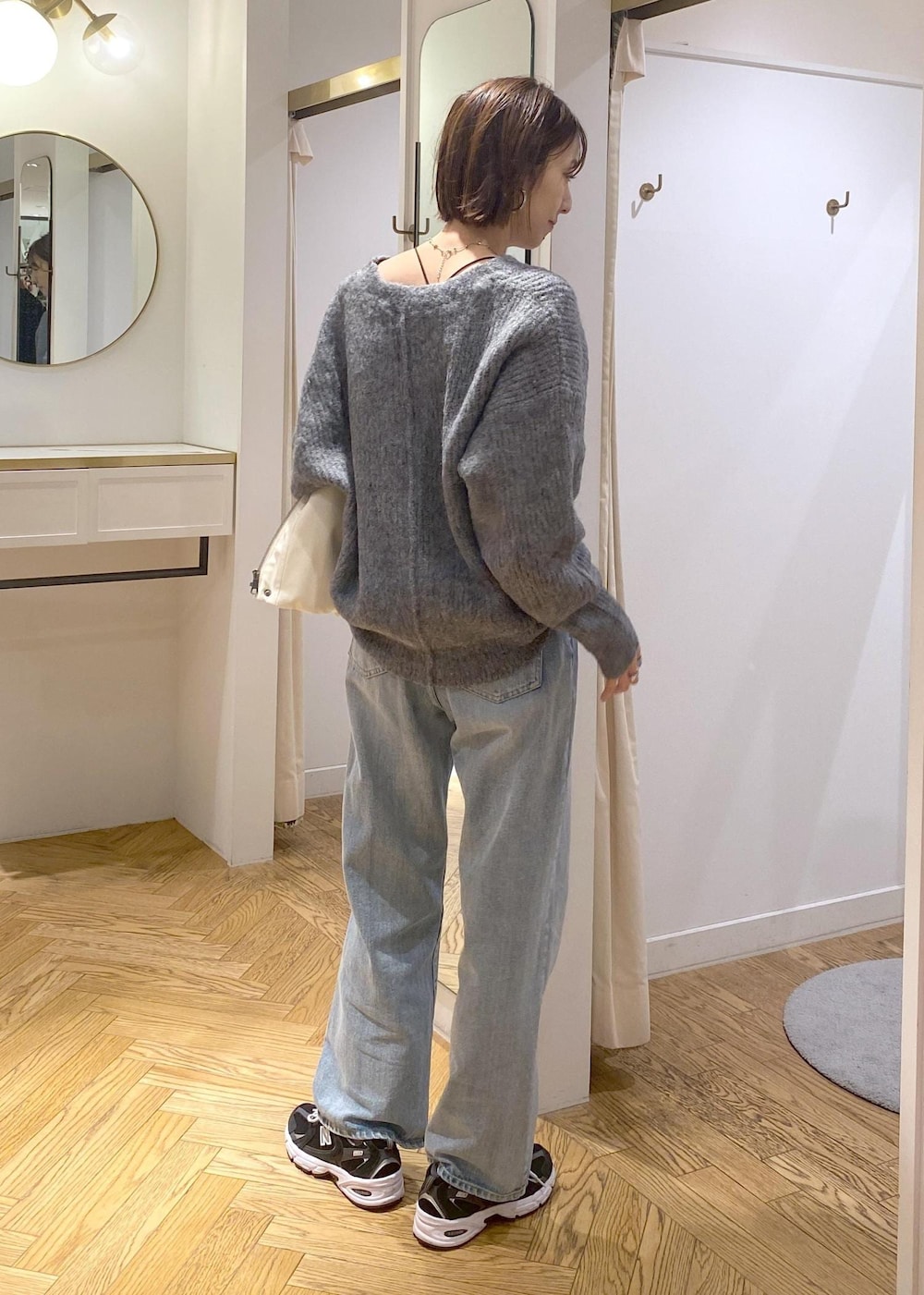 シルバー系のショルダーバッグ、ブルー系のデニムパンツ、グレー系のカーディガン/ボレロを着用したレディースの冬コーディネートの2枚目の写真