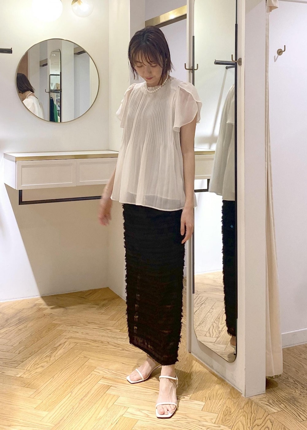 ブラック系のハンドバッグ、ホワイト系のサンダル、ホワイト系のシャツ/ブラウスを着用したレディースの春コーディネートの5枚目の写真