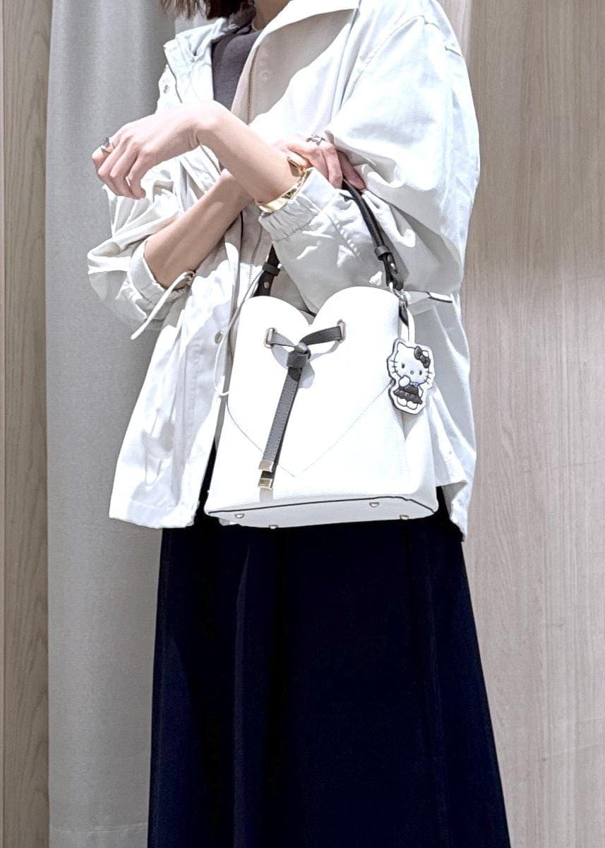 グレー系のニット/セーター、ブルー系のスカート、ホワイト系のナイロンジャケットを着用したレディースの春コーディネートの6枚目の写真