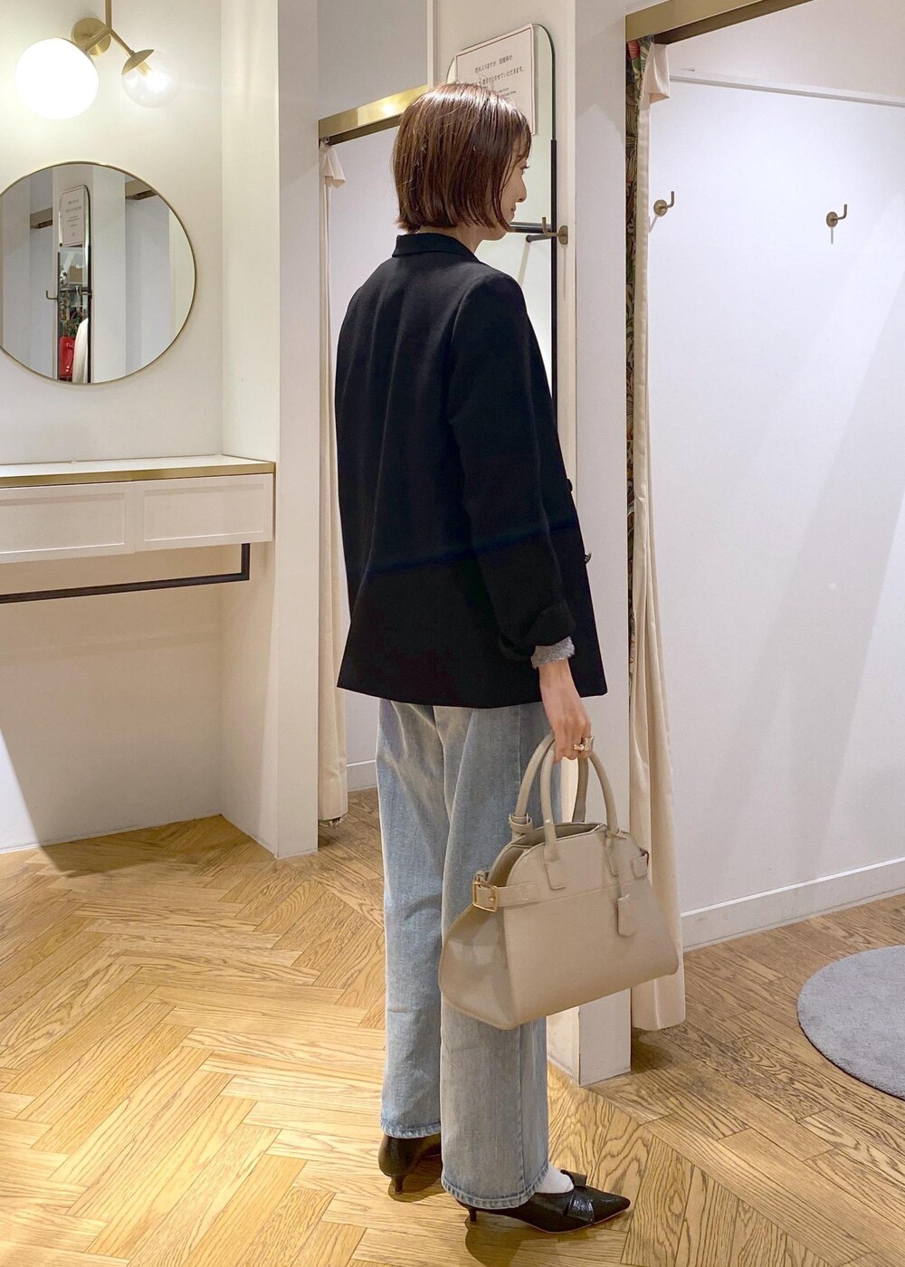 ブラック系のパンプス、グレー系のニット/セーター、ブルー系のデニムパンツを着用したレディースの冬コーディネートの4枚目の写真