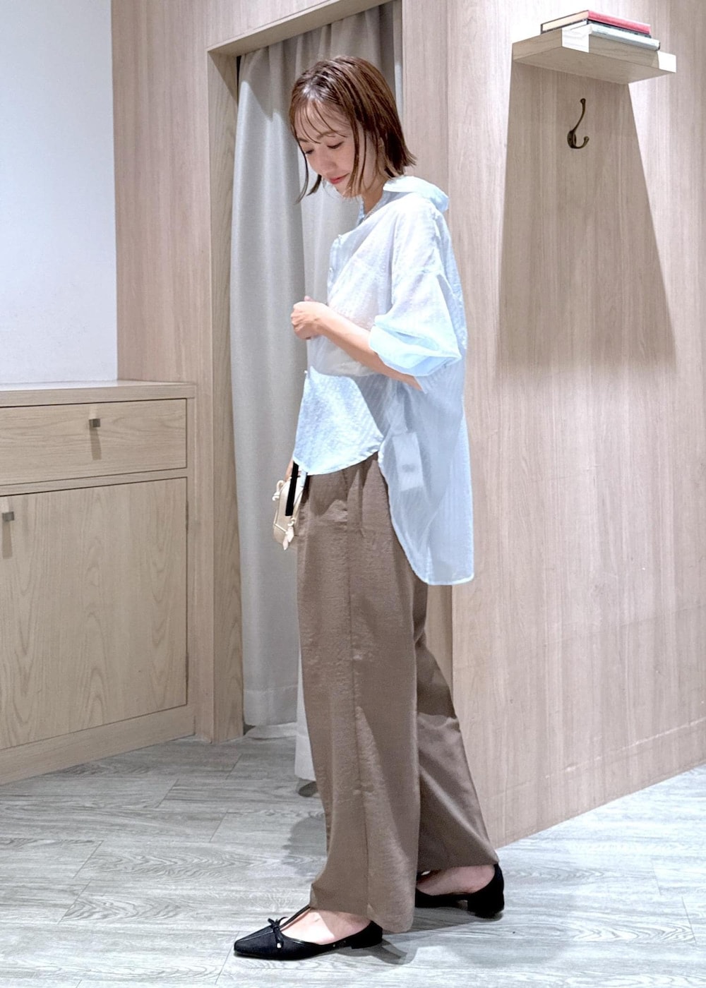 グリーン系のスラックス、ブラック系のパンプス、ベージュ系のボストンバッグを着用したレディースの秋コーディネートの3枚目の写真