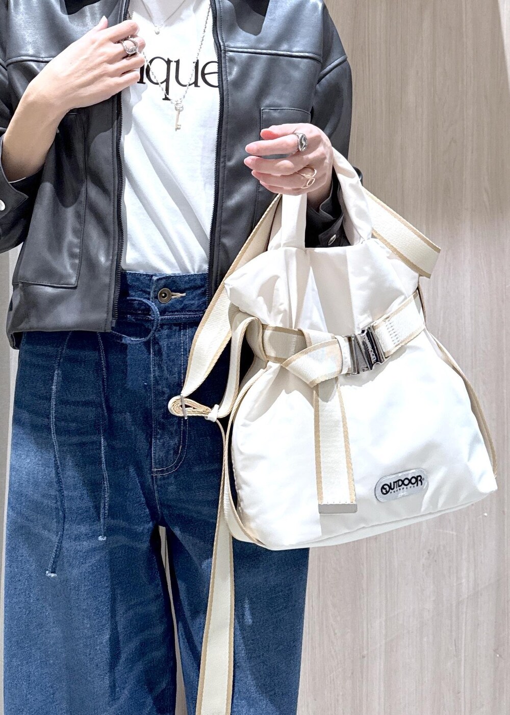 ホワイト系のトートバッグ、ブラック系のブルゾン、ホワイト系のTシャツ/カットソーを着用したレディースの冬コーディネートの6枚目の写真