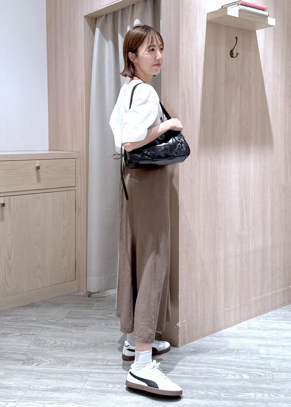 グリーン系のスカート、ホワイト系のTシャツ/カットソー、ブラック系のハンドバッグを着用したレディースの春コーディネートの3枚目の写真