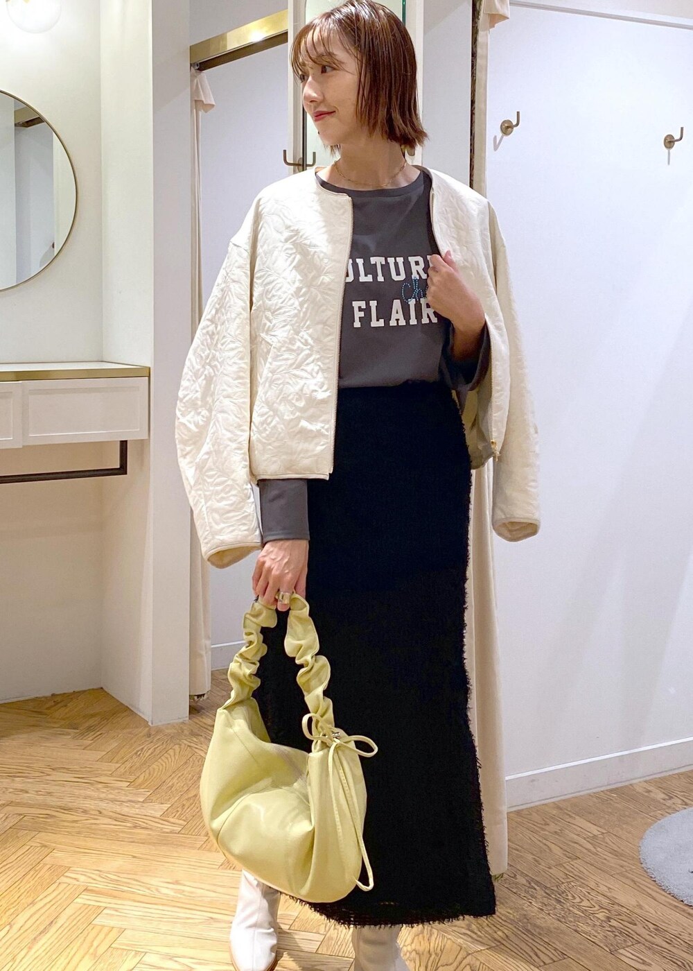 ホワイト系のブーツ、ブラック系のスカート、ホワイト系のブルゾンを着用したレディースの秋コーディネートの8枚目の写真