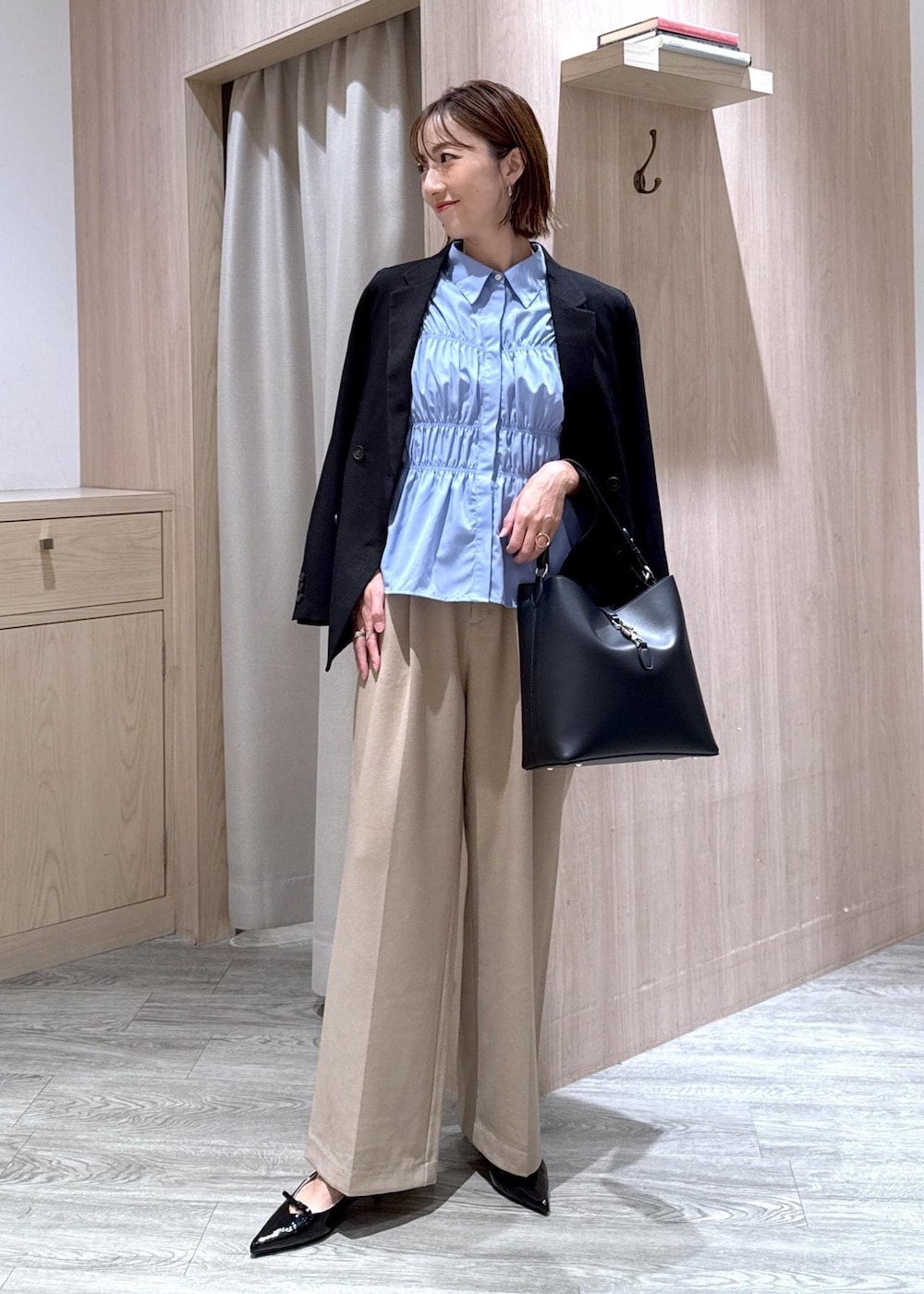 ブラック系のパンプス、ブラック系のトートバッグ、ブルー系のシャツ/ブラウスを着用したレディースの秋コーディネートの2枚目の写真