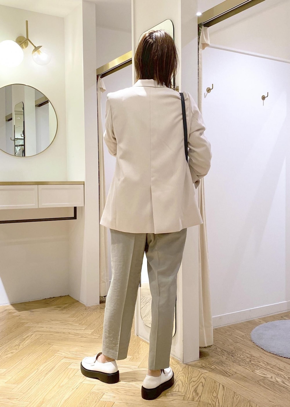 ホワイト系のローファー、ブラック系のショルダーバッグ、ブルー系のニット/セーターを着用したレディースの春コーディネートの2枚目の写真