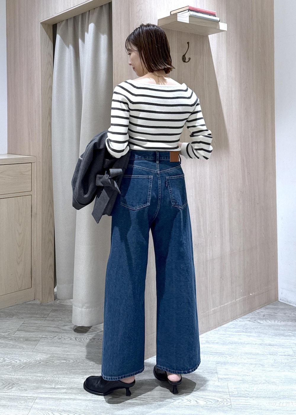 ブルー系のデニムパンツ、グレー系のテーラードジャケット、ホワイト系のショルダーバッグを着用したレディースの冬コーディネートの5枚目の写真