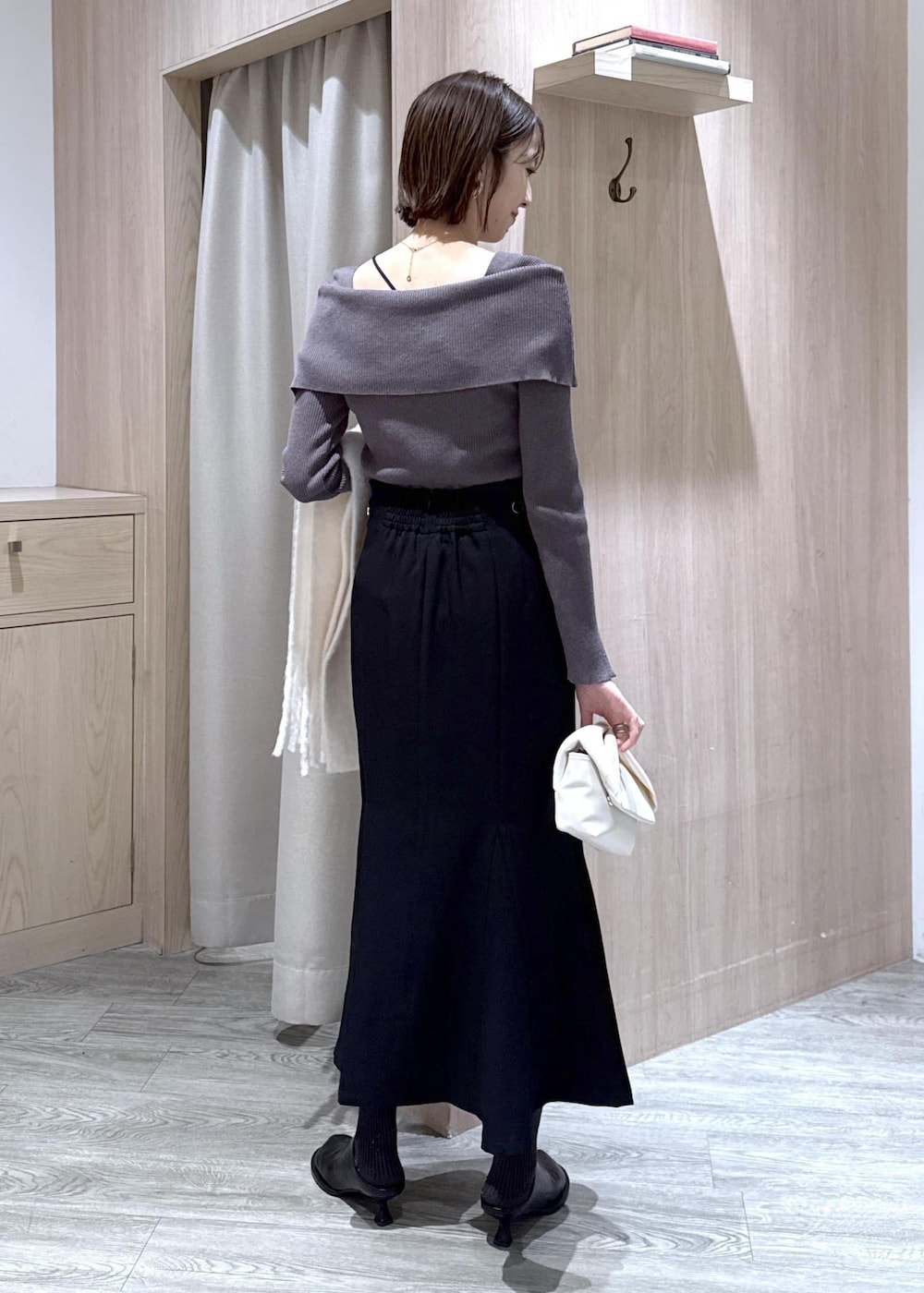 ブラック系のスカート、グレー系のニット/セーター、ホワイト系のショルダーバッグを着用したレディースの冬コーディネートの3枚目の写真