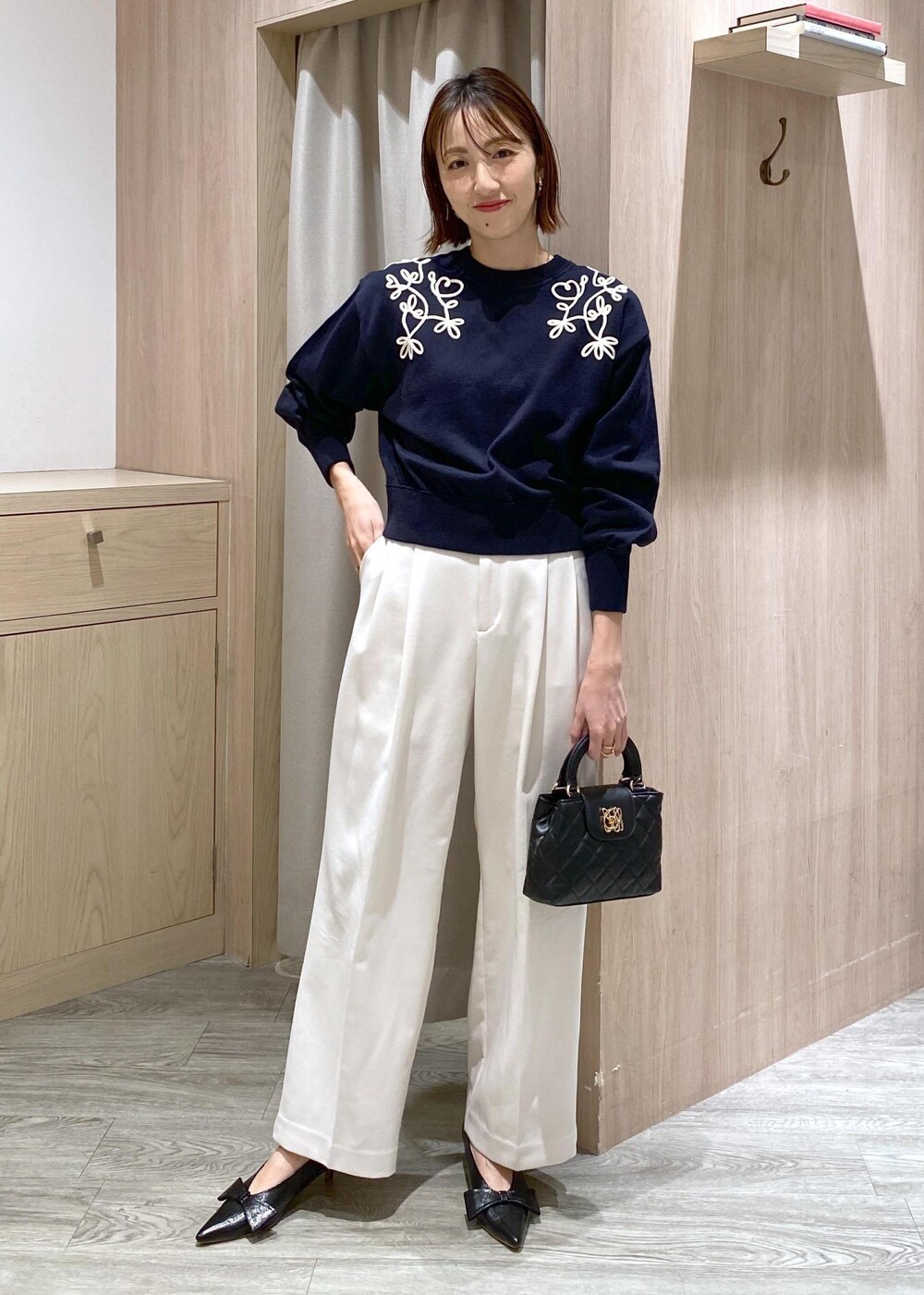 ブラック系のパンプス、ブルー系のニット/セーター、ホワイト系のスラックスを着用したレディースの冬コーディネートの2枚目の写真