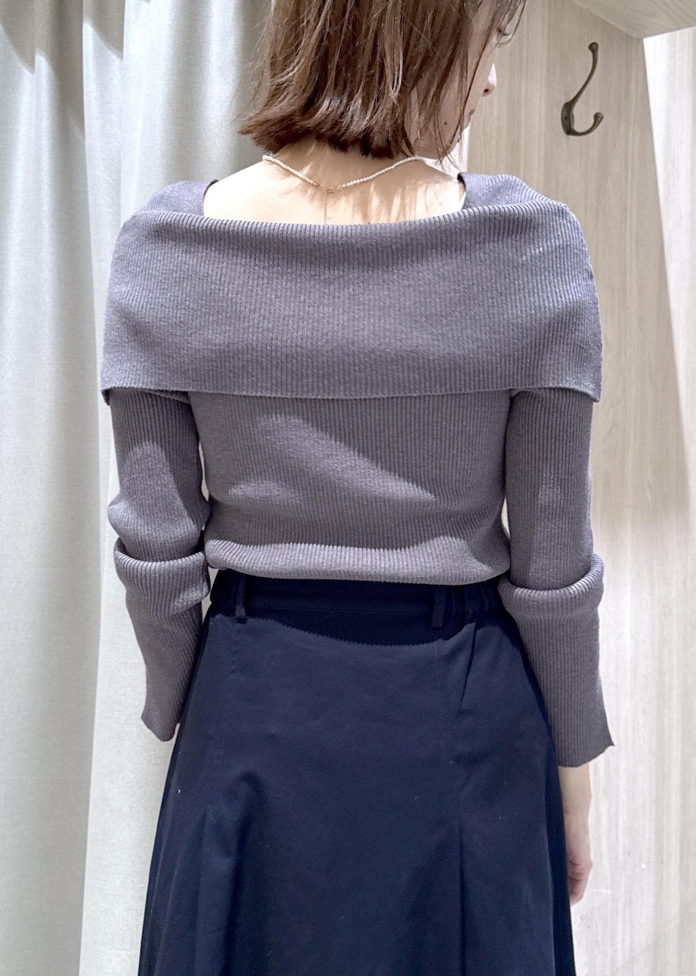 グレー系のニット/セーター、ブルー系のスカート、ホワイト系のナイロンジャケットを着用したレディースの春コーディネートの9枚目の写真