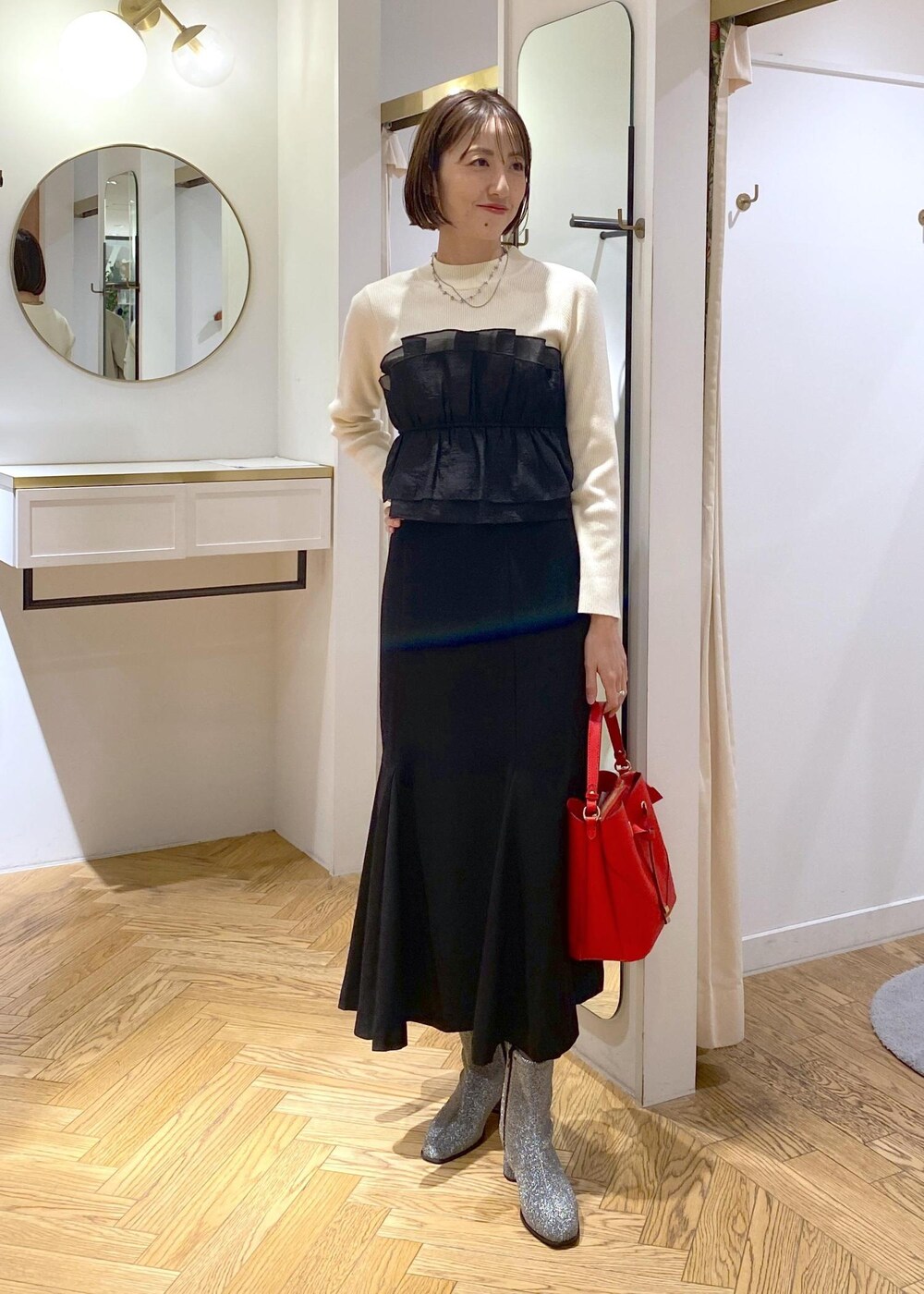 シルバー系のブーツ、ブラック系のスカート、ホワイト系のニット/セーターを着用したレディースの冬コーディネートの2枚目の写真