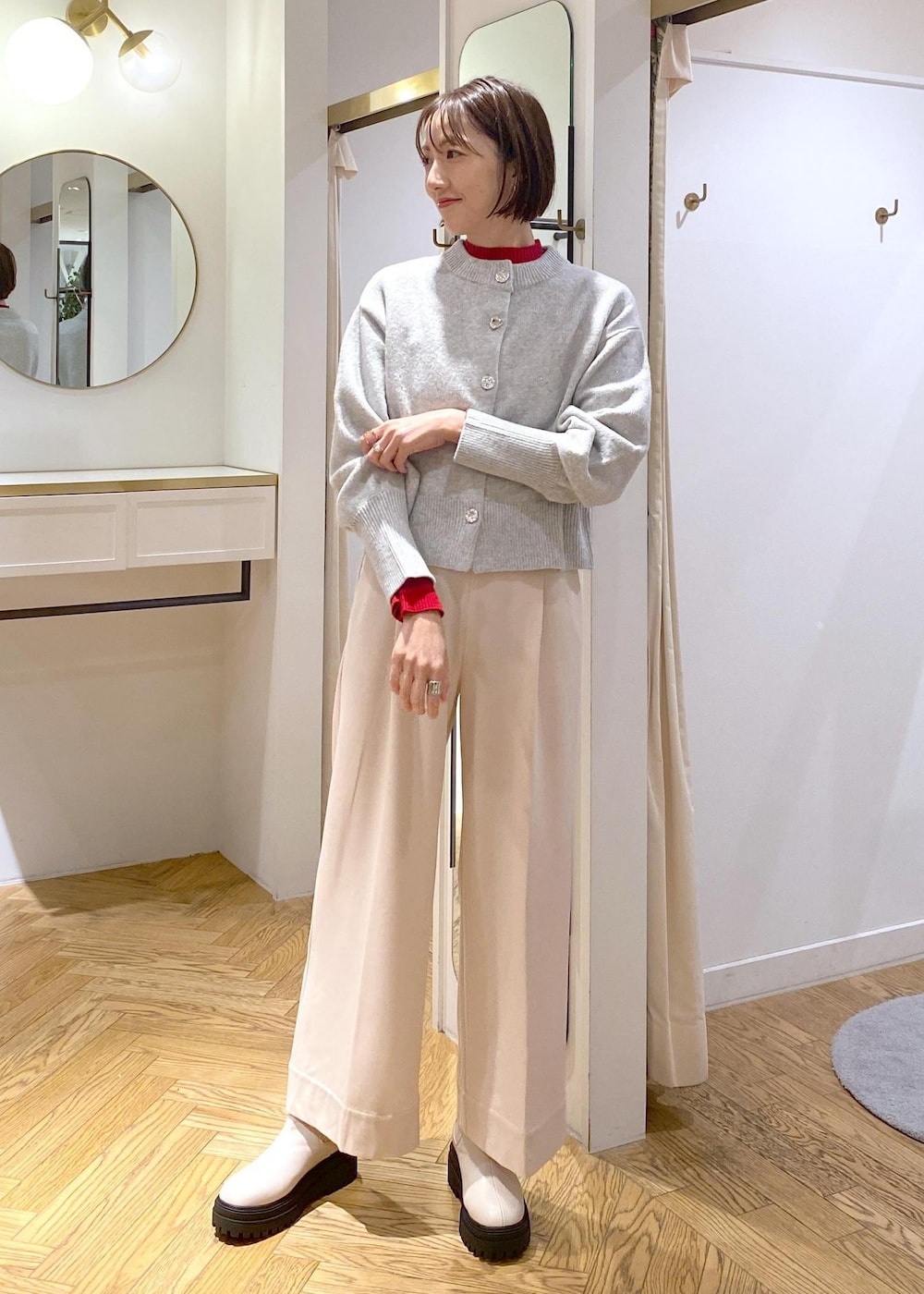 ホワイト系のブーツ、グレー系のカーディガン/ボレロ、レッド系のニット/セーターを着用したレディースの冬コーディネートの8枚目の写真