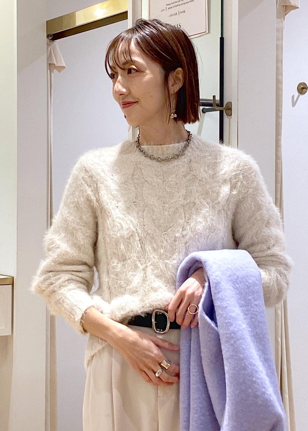 ベージュ系のニット/セーター、ホワイト系のスラックス、ホワイト系のショルダーバッグを着用したレディースの冬コーディネートの7枚目の写真