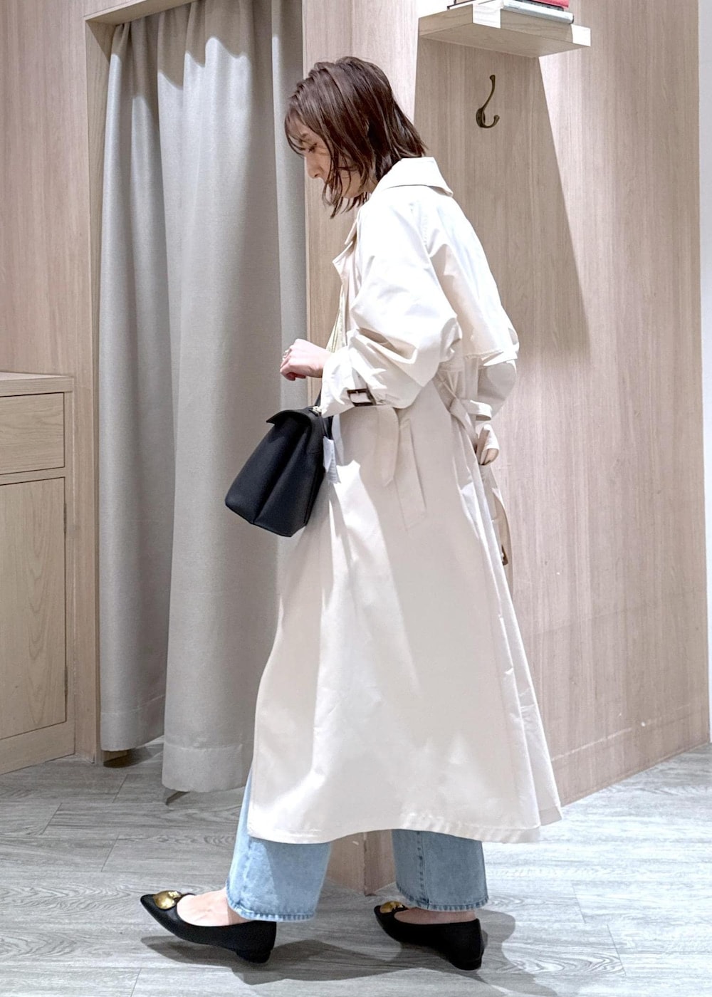 ブラック系のハンドバッグ、ブラック系のバレエシューズ、ホワイト系のトレンチコートを着用したレディースの春コーディネートの3枚目の写真
