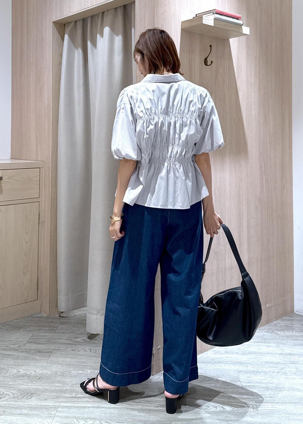 ブラック系のショルダーバッグ、ブラック系のサンダル、ブルー系のデニムパンツを着用したレディースの夏コーディネートの3枚目の写真