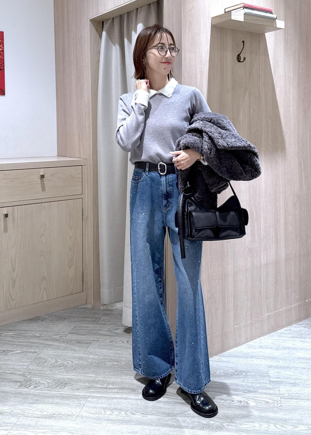 グレー系のブルゾン、グレー系のニット/セーター、ブルー系のデニムパンツを着用したレディースの冬コーディネートの5枚目の写真