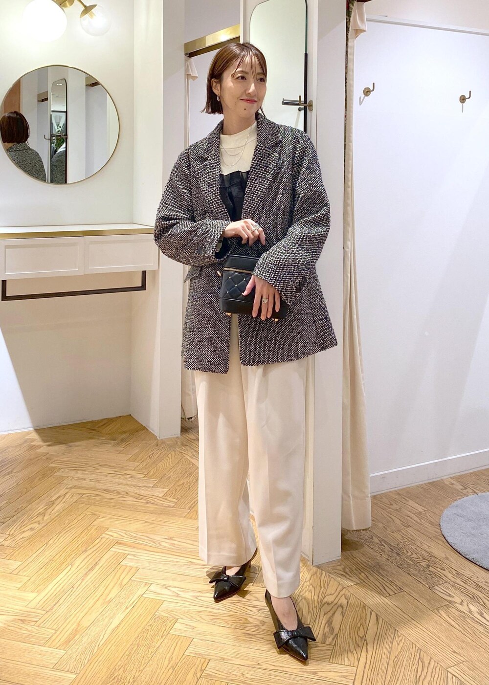 ブラック系のパンプス、ホワイト系のニット/セーター、ホワイト系のスラックスを着用したレディースの冬コーディネートの10枚目の写真