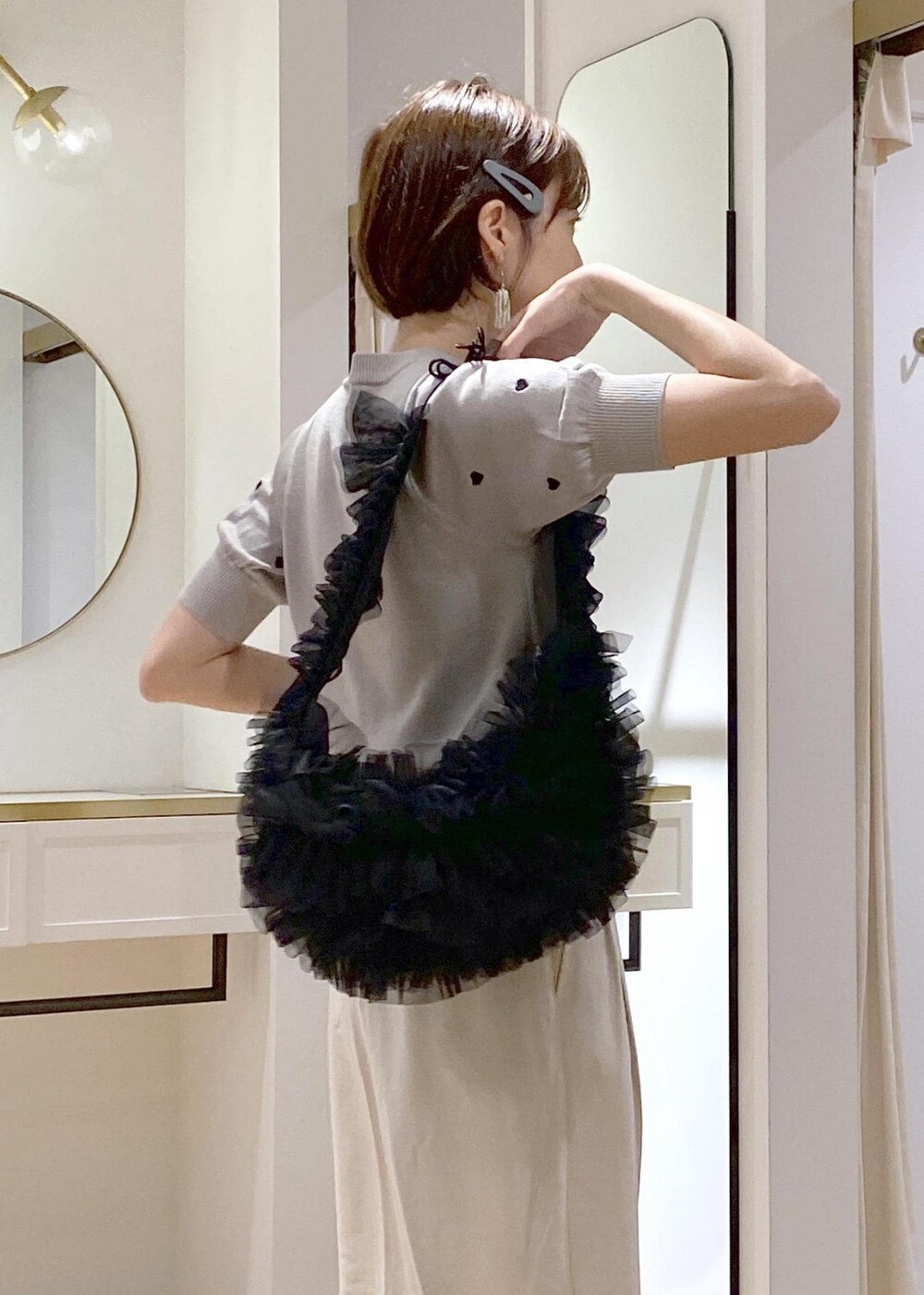 ブラック系のショルダーバッグ、グレー系のニット/セーター、ホワイト系のスラックスを着用したレディースの夏コーディネートの5枚目の写真