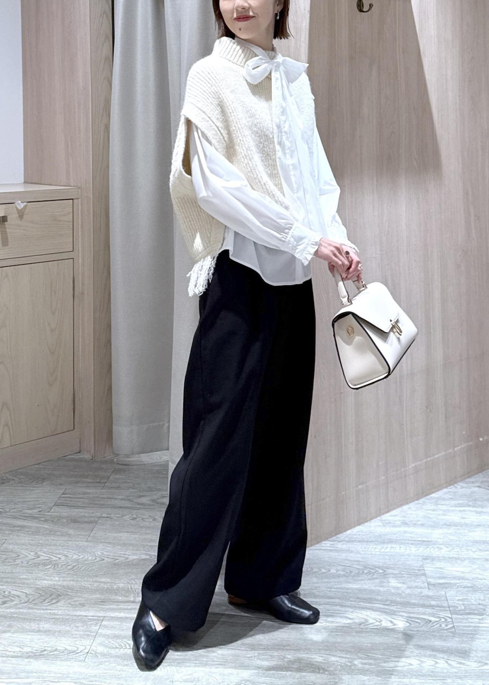 ブラック系のスラックス、ホワイト系のベスト、ホワイト系のシャツ/ブラウスを着用したレディースの秋コーディネートの8枚目の写真