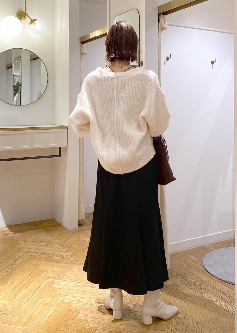ホワイト系のブーツ、ブラック系のスカート、ブラウン系のショルダーバッグを着用したレディースの秋コーディネートの3枚目の写真