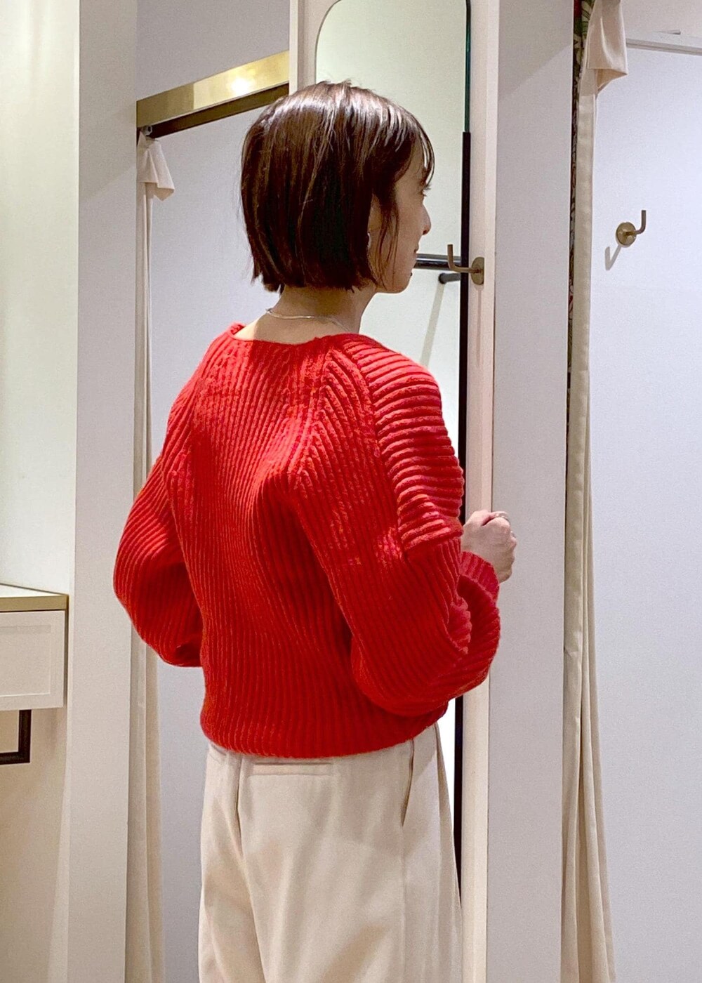 レッド系のニット/セーター、ホワイト系のスラックス、ブラック系のハンドバッグを着用したレディースの冬コーディネートの8枚目の写真