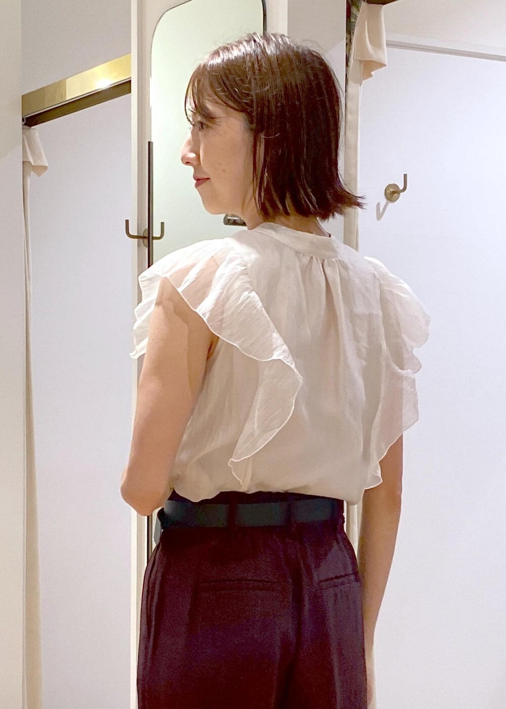 ブラック系のハンドバッグ、ブラック系のパンプス、ブラウン系のスラックスを着用したレディースの夏コーディネートの7枚目の写真