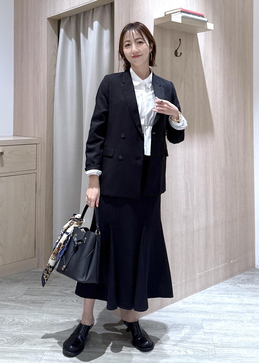 ブラック系のショルダーバッグ、ブラック系のスカート、ブラック系のテーラードジャケットを着用したレディースの冬コーディネートの3枚目の写真