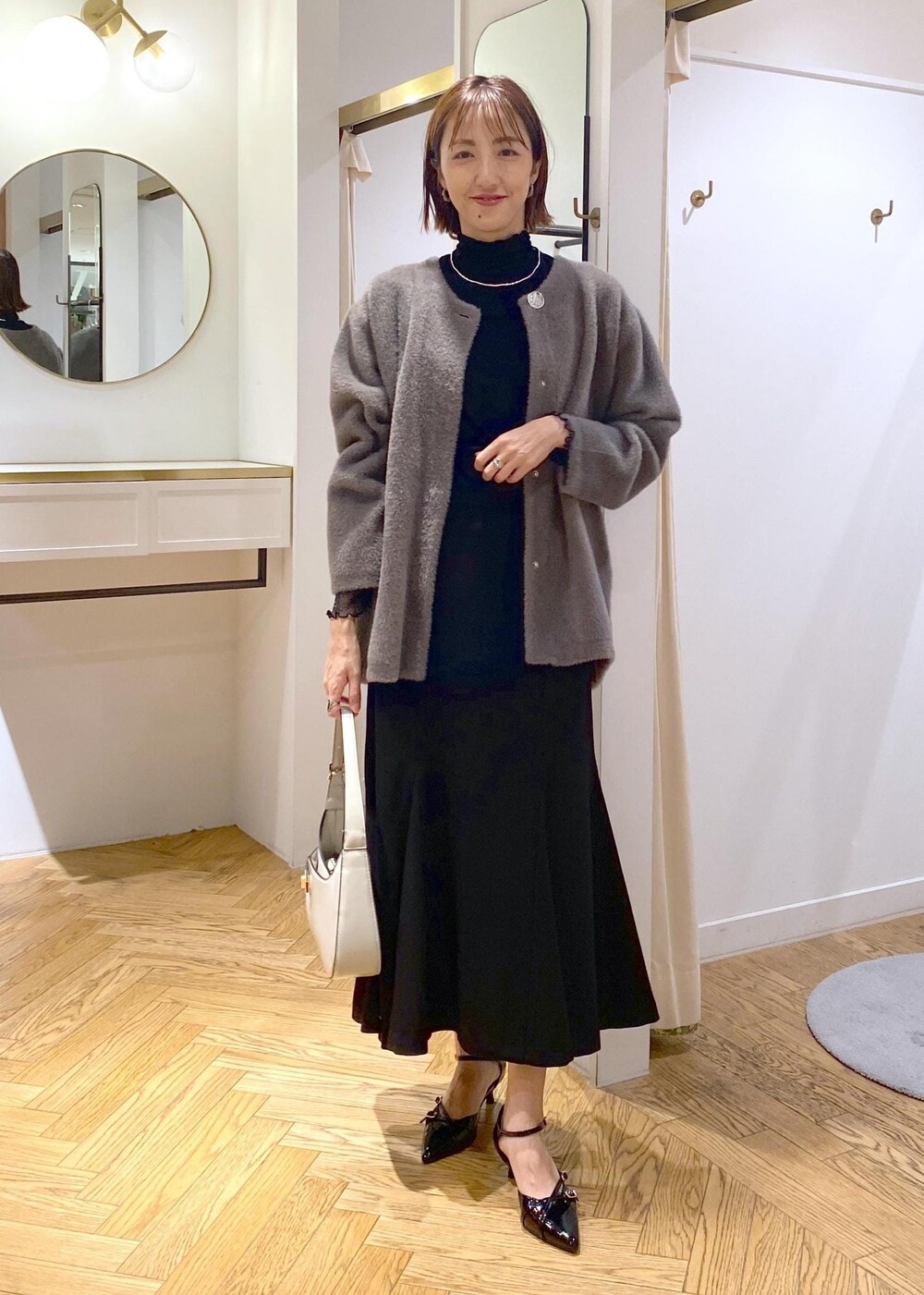 ブラック系のパンプス、ブラック系のスカート、ブラウン系のその他アウターを着用したレディースの秋コーディネートの9枚目の写真