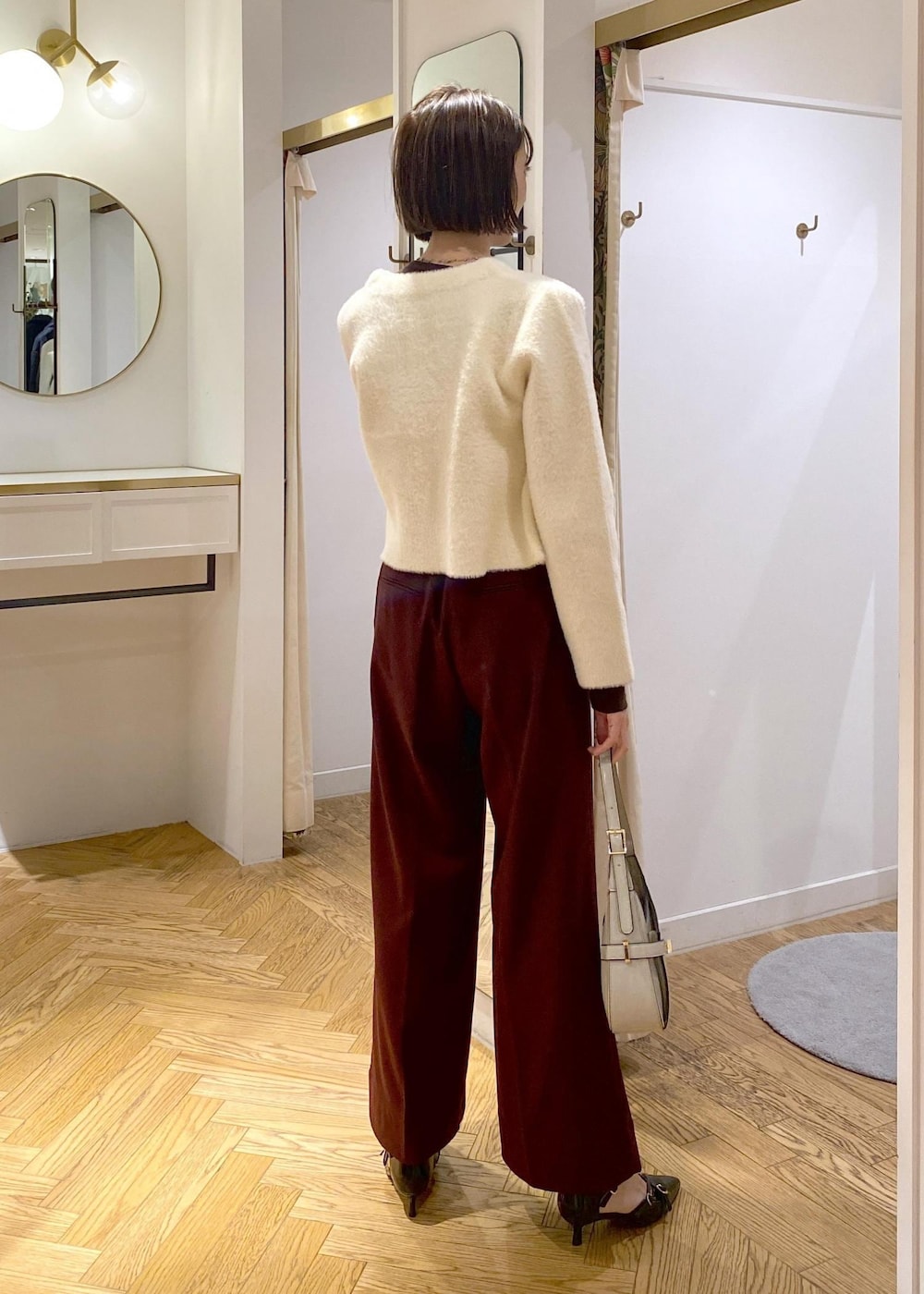 ホワイト系のハンドバッグ、ブラック系のパンプス、ブラウン系のその他パンツを着用したレディースの冬コーディネートの3枚目の写真