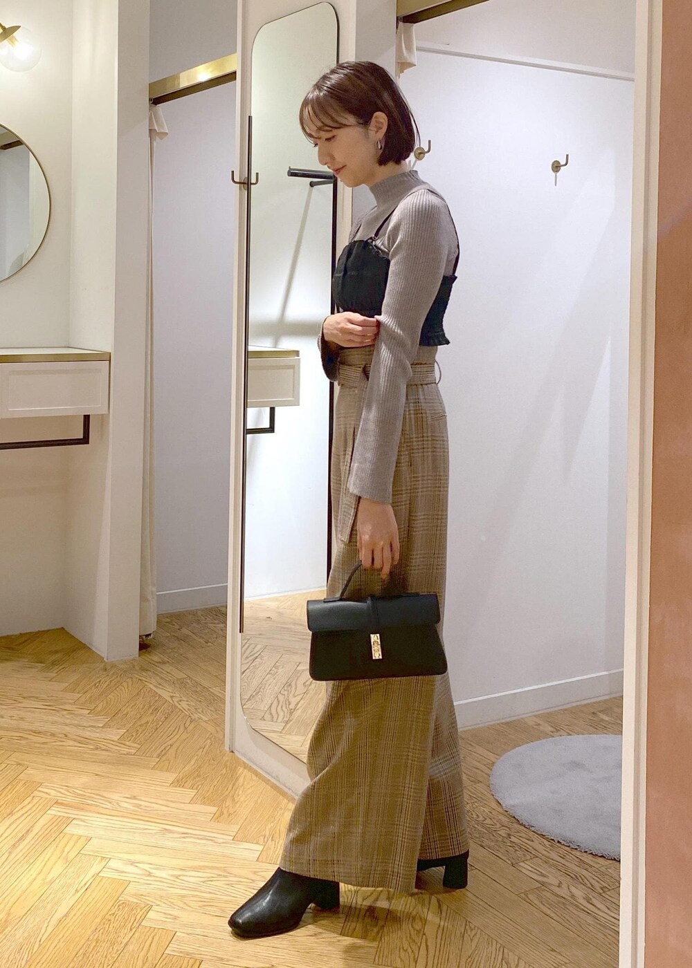 ブラック系のショルダーバッグ、ブラック系のブーツ、ベージュ系のスラックスを着用したレディースの秋コーディネートの2枚目の写真