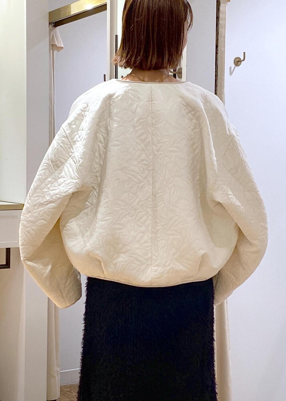 ホワイト系のブーツ、ブラック系のスカート、ホワイト系のブルゾンを着用したレディースの秋コーディネートの6枚目の写真