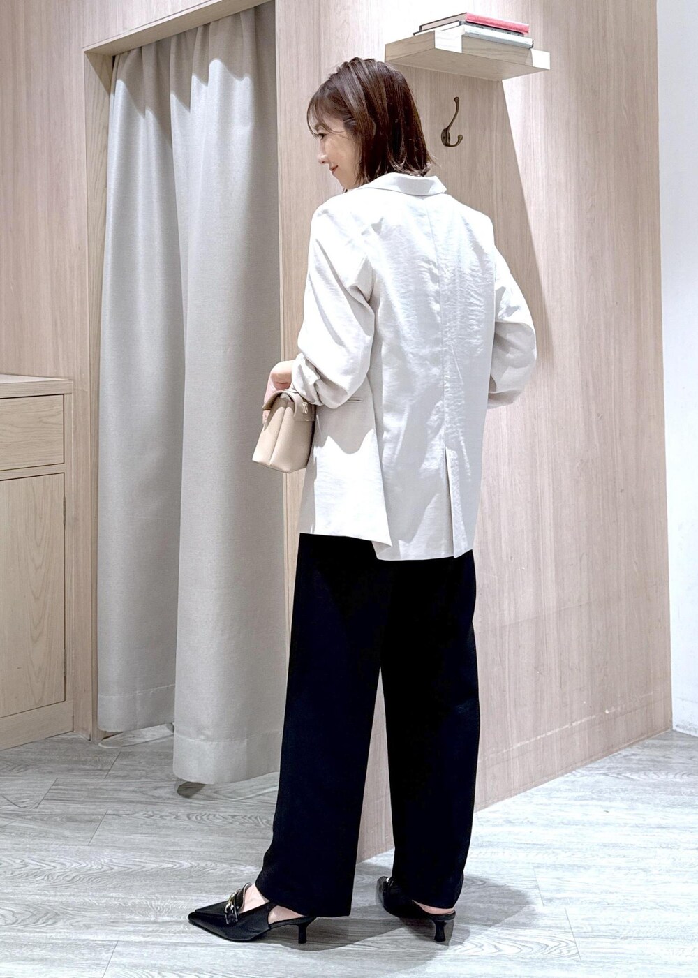 ベージュ系のショルダーバッグ、ブラック系のパンプス、ホワイト系のテーラードジャケットを着用したレディースの春コーディネートの4枚目の写真