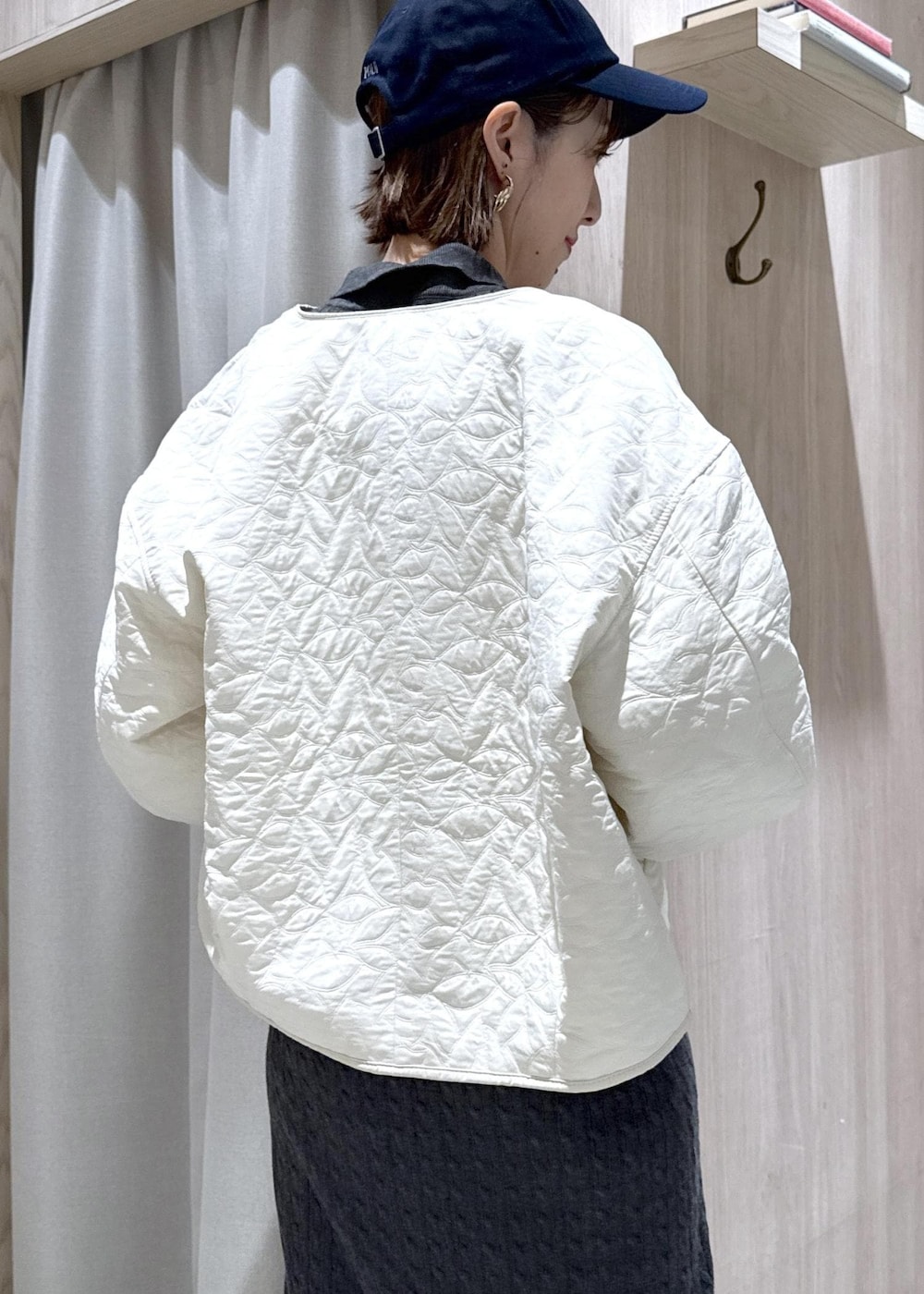 ブラック系のショルダーバッグ、ブラック系のブーツ、ホワイト系のブルゾンを着用したレディースの秋コーディネートの7枚目の写真