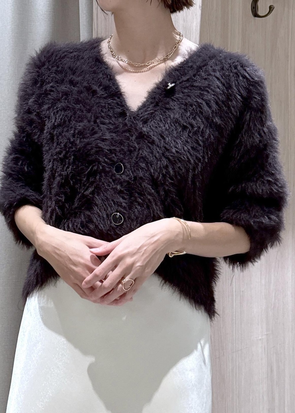 ブラック系のブーツ、ホワイト系のスカート、グレー系のカーディガン/ボレロを着用したレディースの冬コーディネートの6枚目の写真