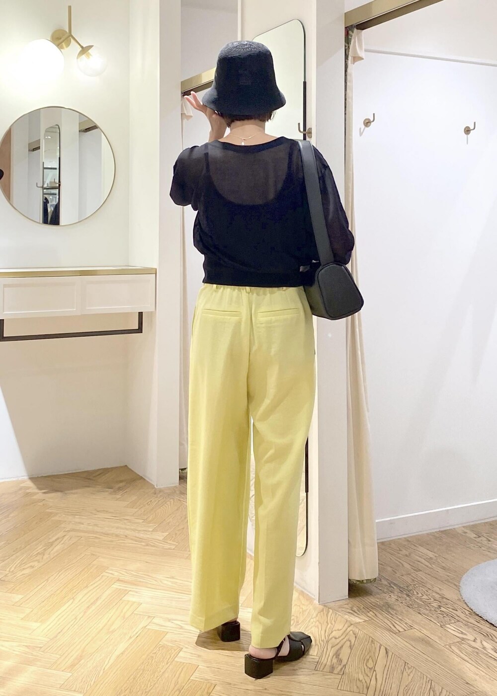 ブラック系のキャミソール、イエロー系のスラックス、ブラック系のショルダーバッグを着用したレディースの夏コーディネートの3枚目の写真