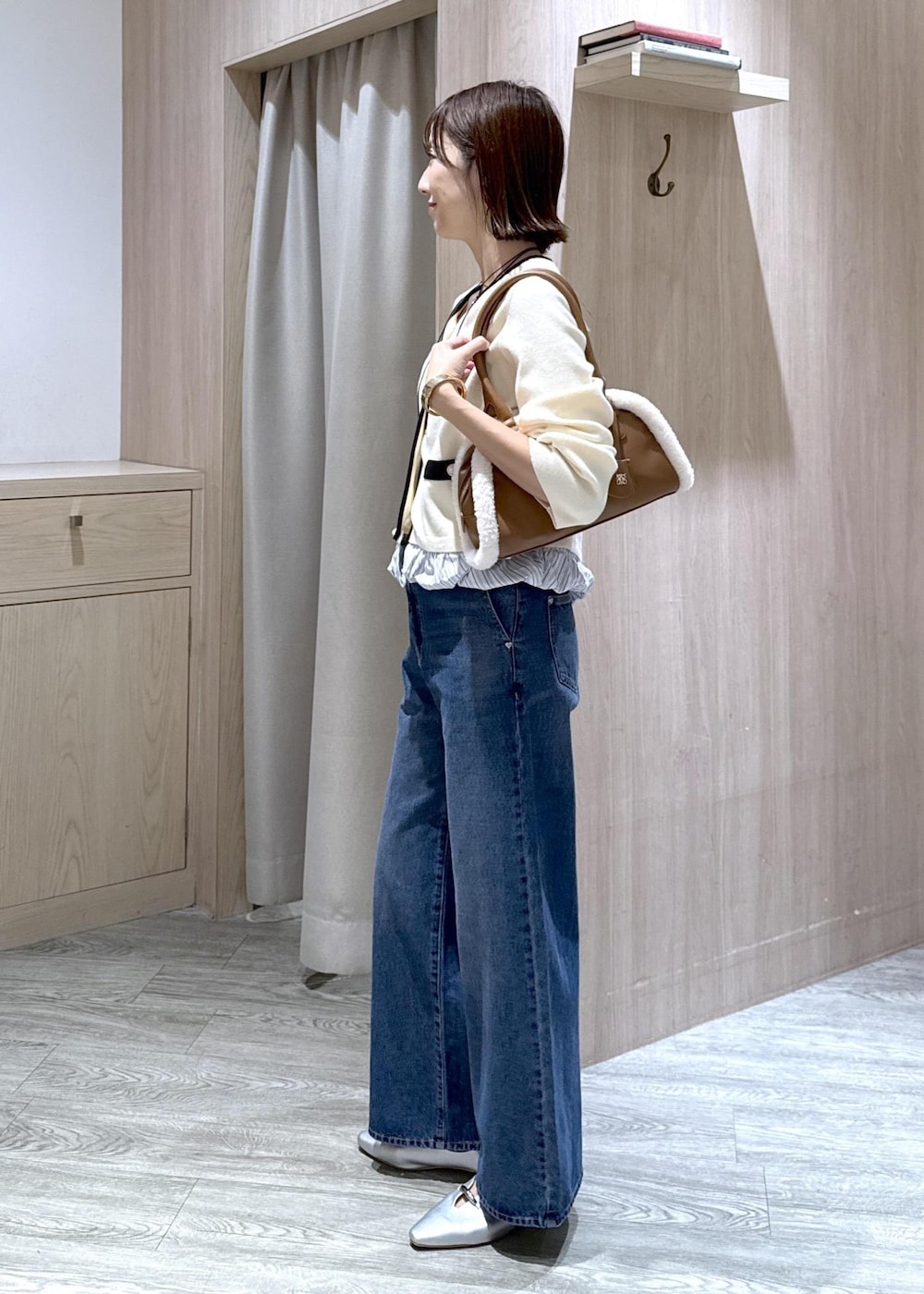 シルバー系のパンプス、ブルー系のデニムパンツ、イエロー系のボストンバッグを着用したレディースの秋コーディネートの3枚目の写真