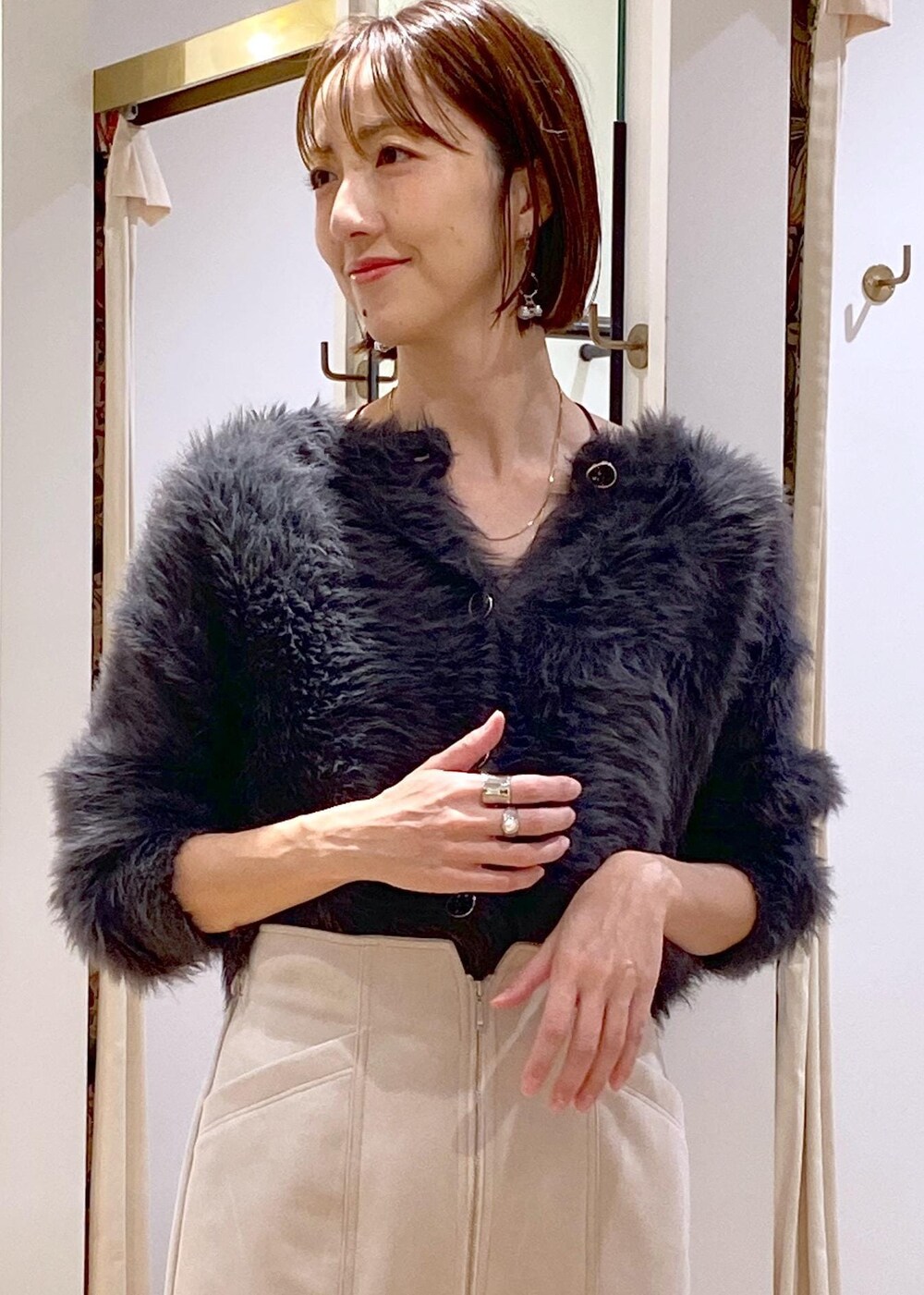 ブラック系のブーツ、ベージュ系のスカート、グレー系のカーディガン/ボレロを着用したレディースの冬コーディネートの7枚目の写真