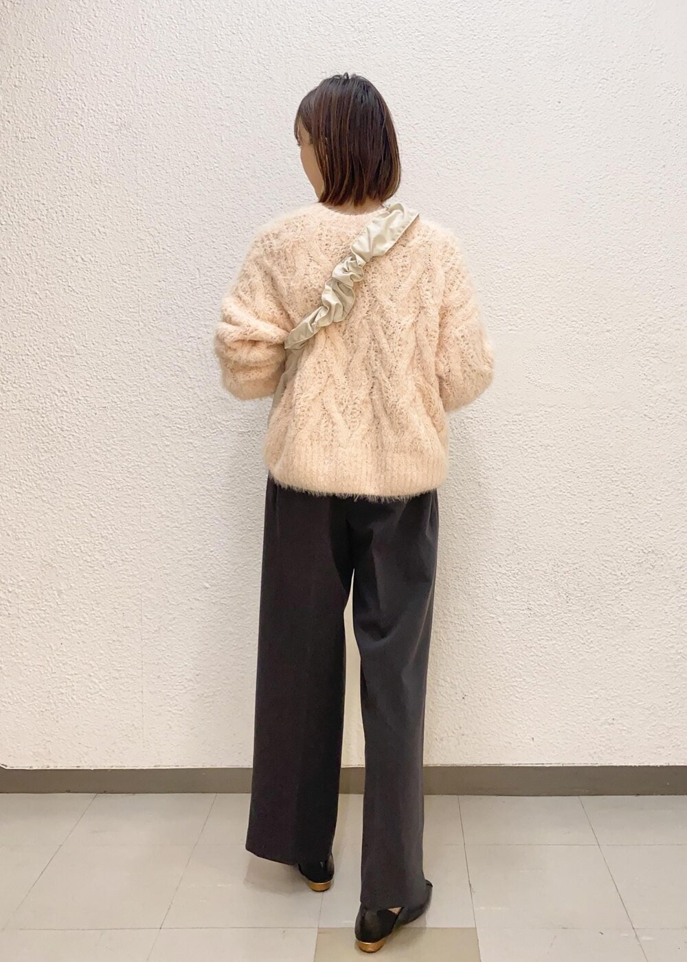 ホワイト系のショルダーバッグ、ピンク系のニット/セーター、グレー系のスラックスを着用したレディースの冬コーディネートの3枚目の写真