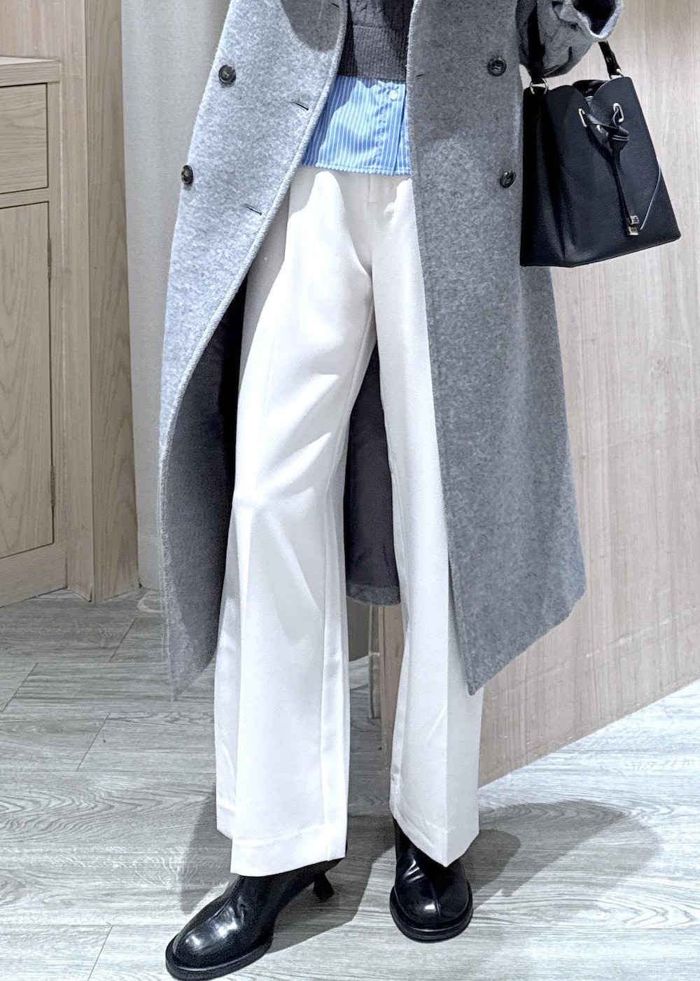 ブラック系のショルダーバッグ、グレー系のその他アウター、ホワイト系のスラックスを着用したレディースの冬コーディネートの6枚目の写真