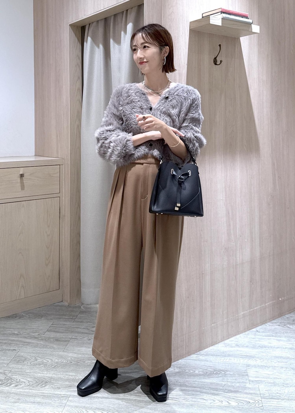 ブラック系のショルダーバッグ、グレー系のカーディガン/ボレロ、ブラック系のブーツを着用したレディースの秋コーディネートの10枚目の写真