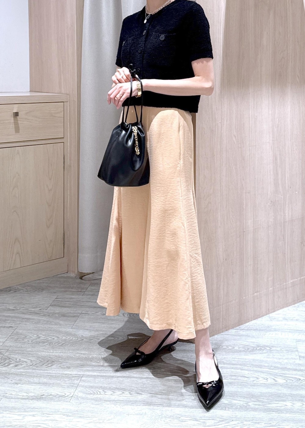 ブラック系のパンプス、オレンジ系のスカート、ブラック系のハンドバッグを着用したレディースの春コーディネートの6枚目の写真