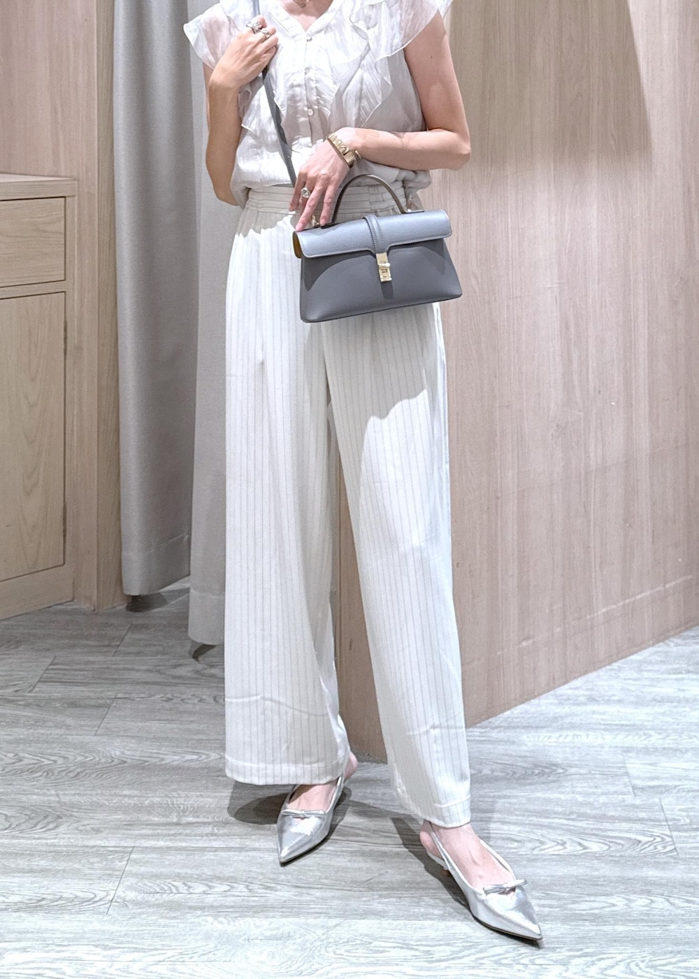 グレー系のショルダーバッグ、シルバー系のパンプス、ベージュ系のシャツ/ブラウスを着用したレディースの夏コーディネートの5枚目の写真