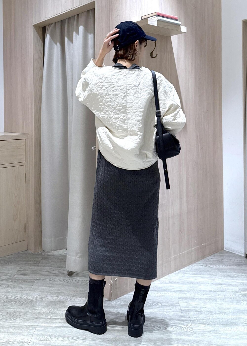 ブラック系のショルダーバッグ、ブラック系のブーツ、ホワイト系のブルゾンを着用したレディースの秋コーディネートの4枚目の写真