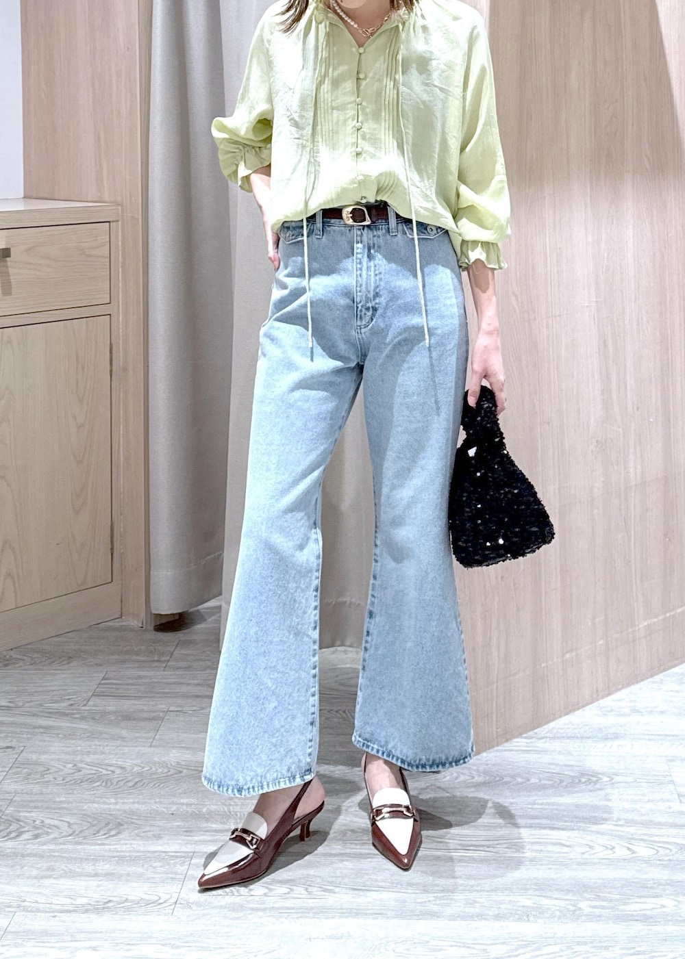 ブルー系のデニムパンツ、ブラウン系のパンプス、ブラック系のハンドバッグを着用したレディースの春コーディネートの5枚目の写真