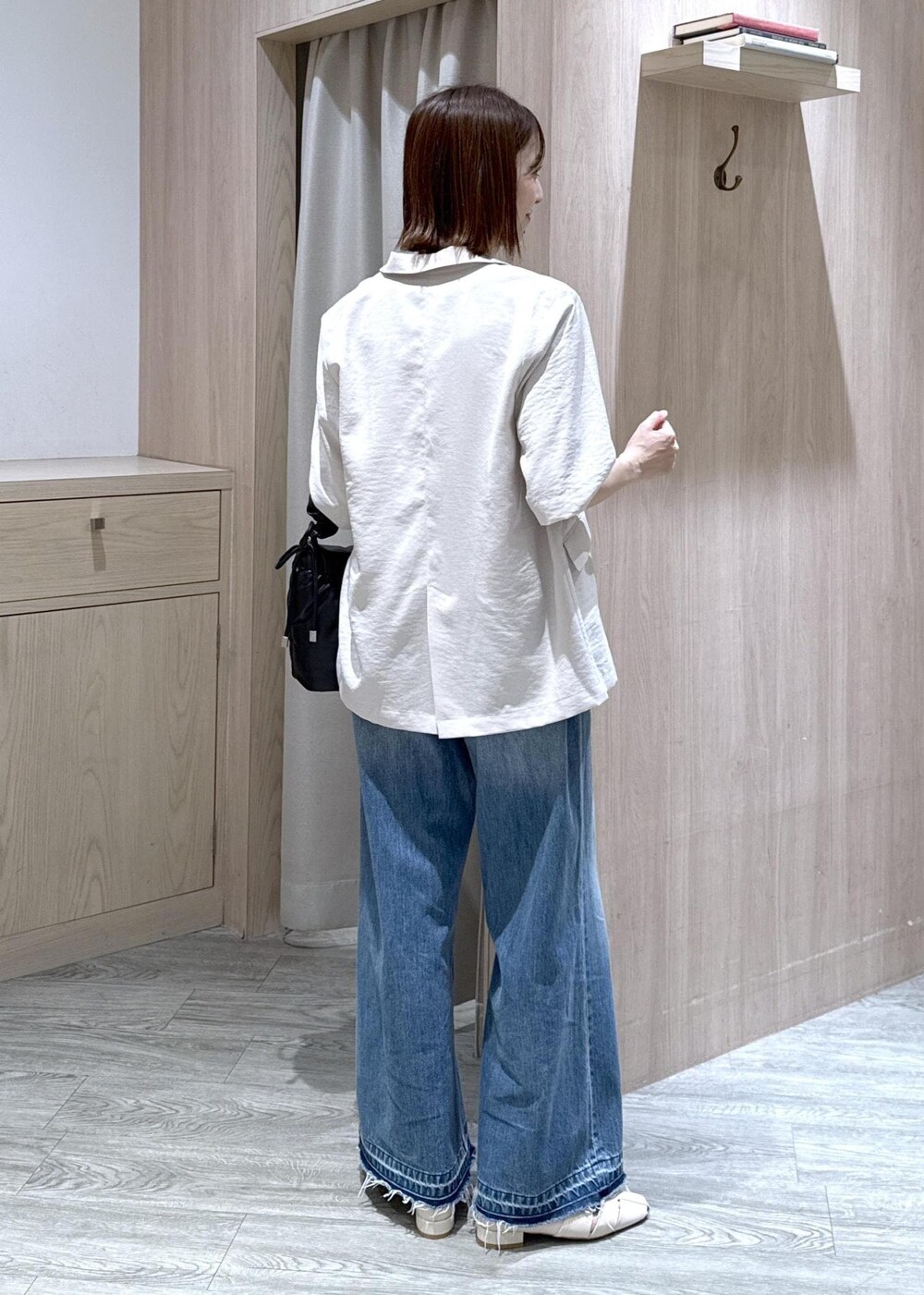 ブルー系のデニムパンツ、ホワイト系のパンプス、ブラック系のショルダーバッグを着用したレディースの春コーディネートの2枚目の写真