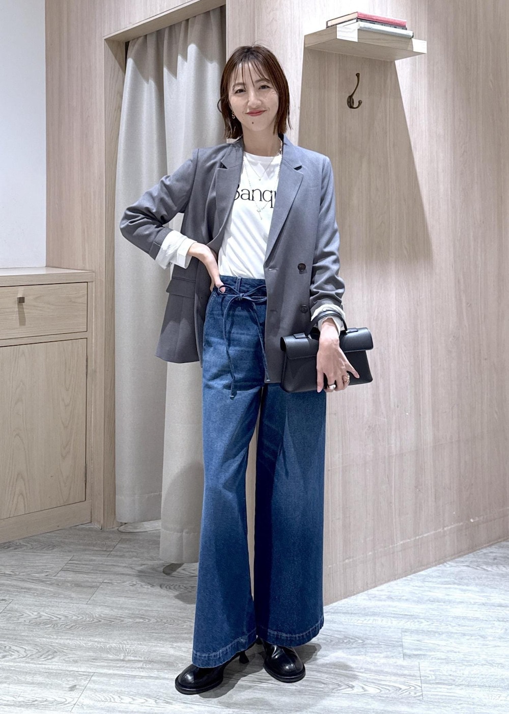 ブラック系のショルダーバッグ、グレー系のテーラードジャケット、ホワイト系のTシャツ/カットソーを着用したレディースの冬コーディネートの2枚目の写真