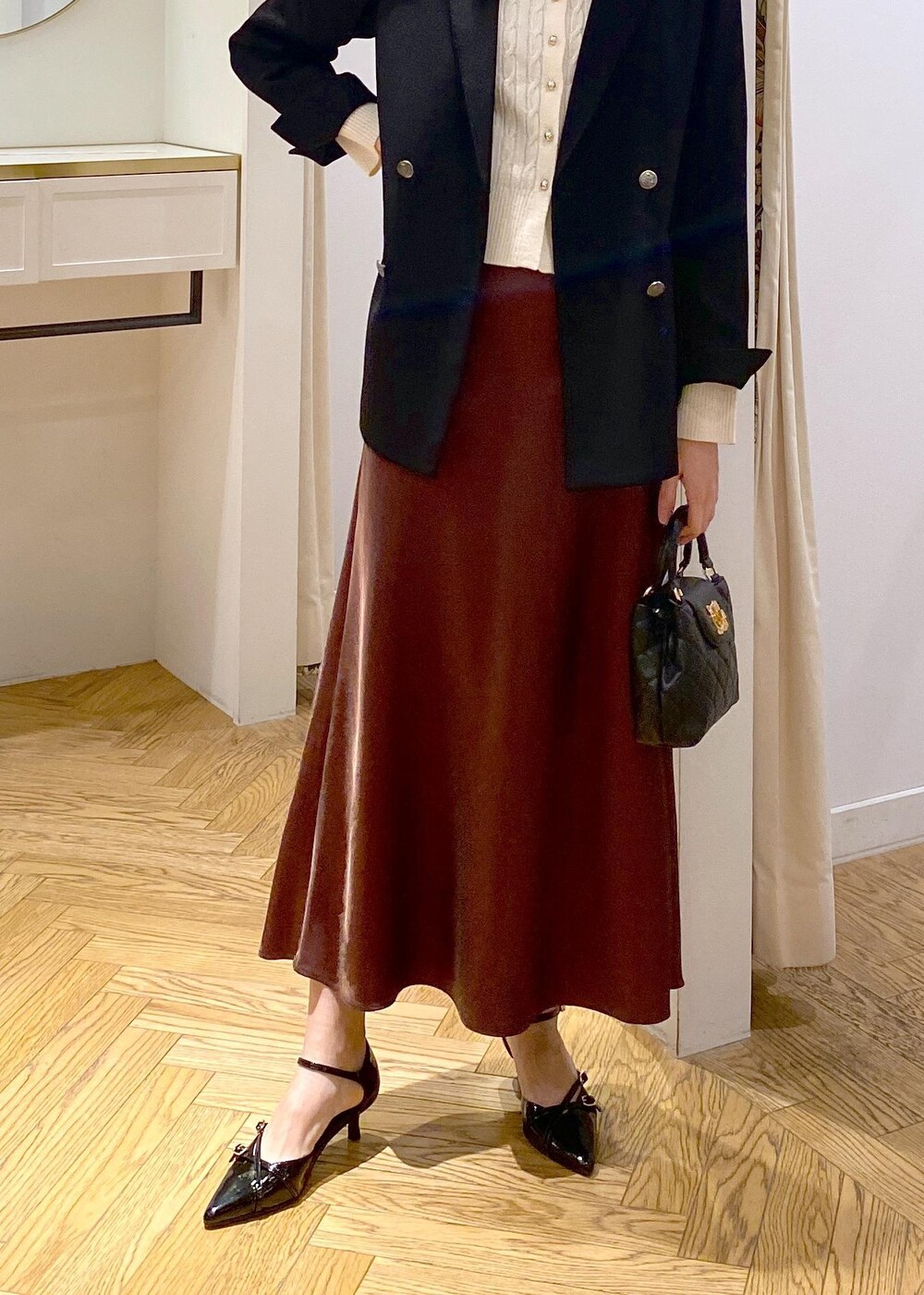 ブラック系のテーラードジャケット、ブラック系のパンプス、ブラウン系のスカートを着用したレディースの冬コーディネートの6枚目の写真